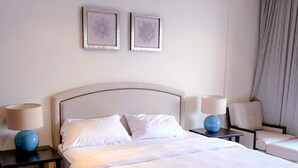 Un lit bien fait, avec du linge de lit blanc, deux tables de chevet avec des lampes et un tapis à motifs.