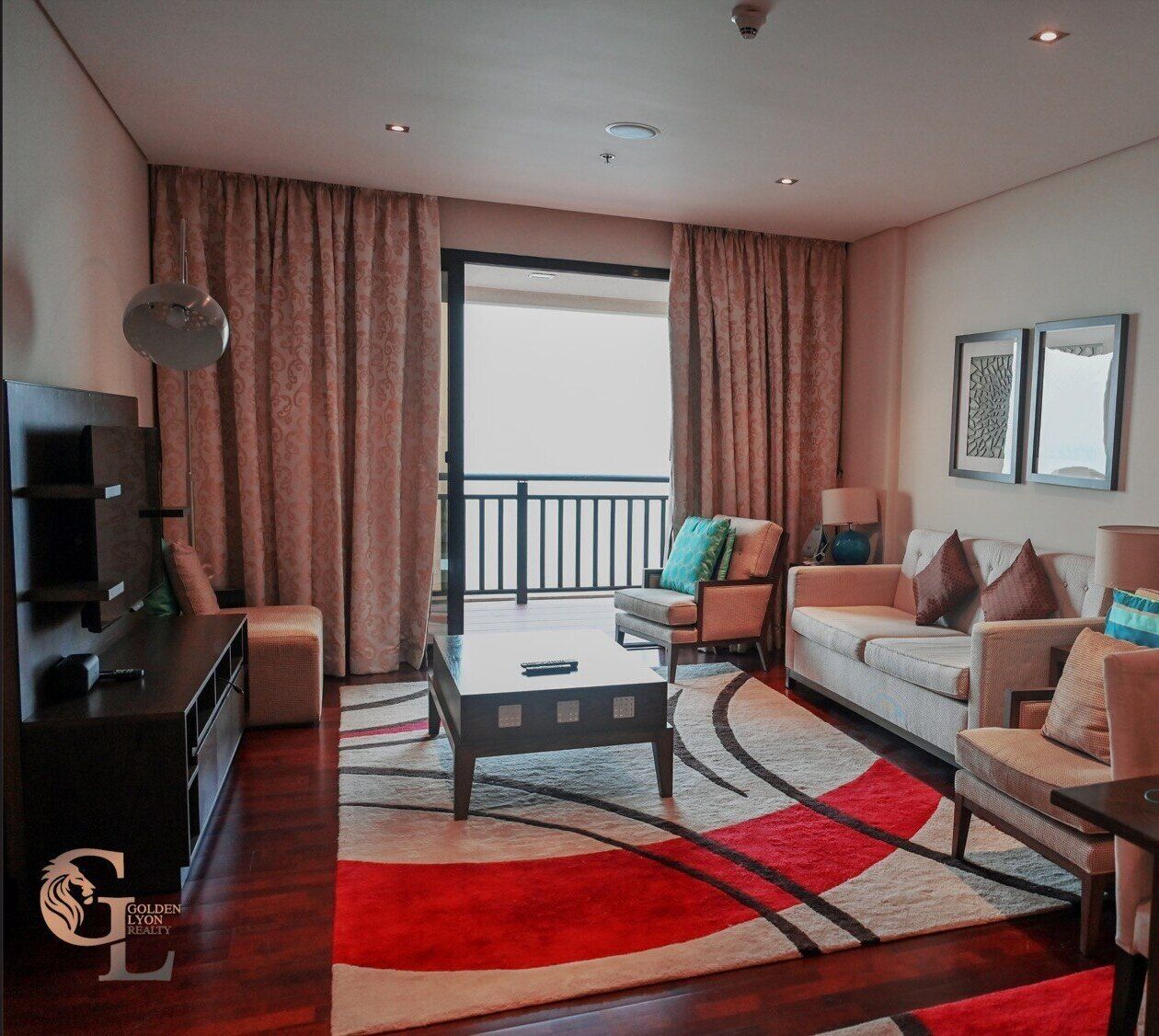 A modern living room with a flat-screen TV, a sofa, a coffee table, and a balcony with curtains.
