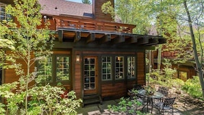 A rustic log cabin with a covered patio area, large windows, and a chimney.
