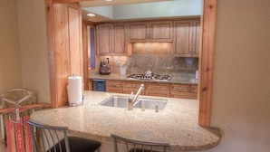 A kitchen with wooden cabinets, granite countertops, a sink, and a stove.