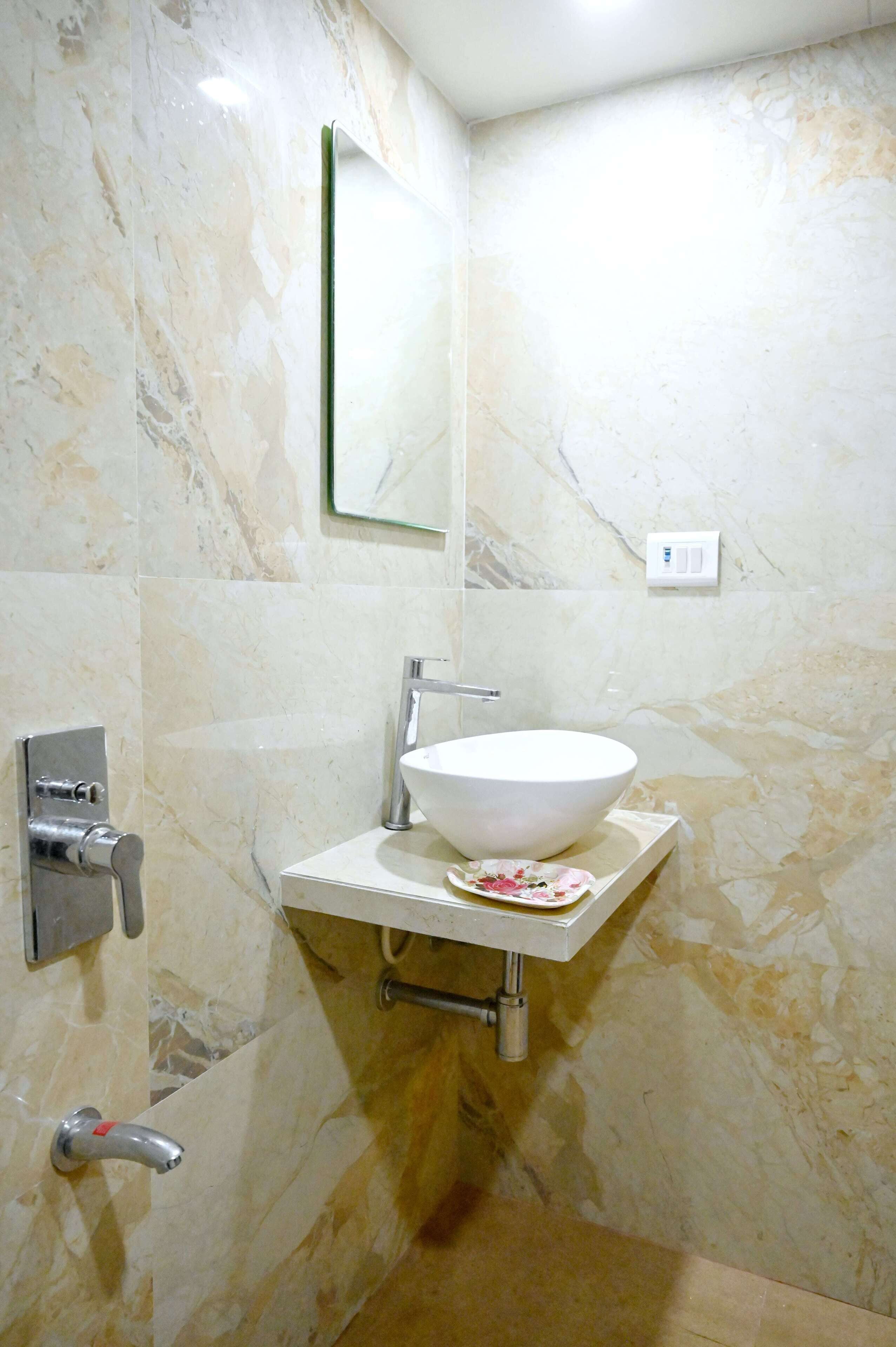A bathroom with a marble wall, a white sink, a mirror, and a towel rack.