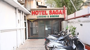 Un hotel llamado "HOTEL SAGAR" con un letrero que indica "LODGING & BORDING". Varias motocicletas están estacionadas al frente.