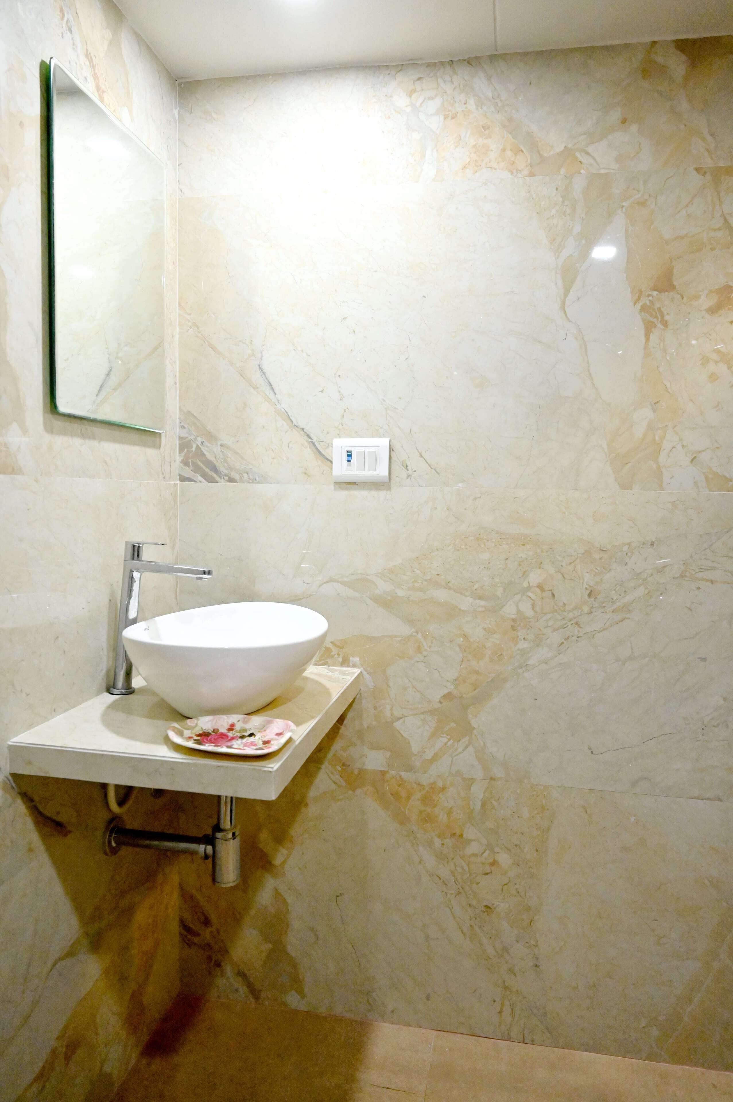 Un bagno con un lavabo a incasso bianco, uno specchio e pareti in marmo.