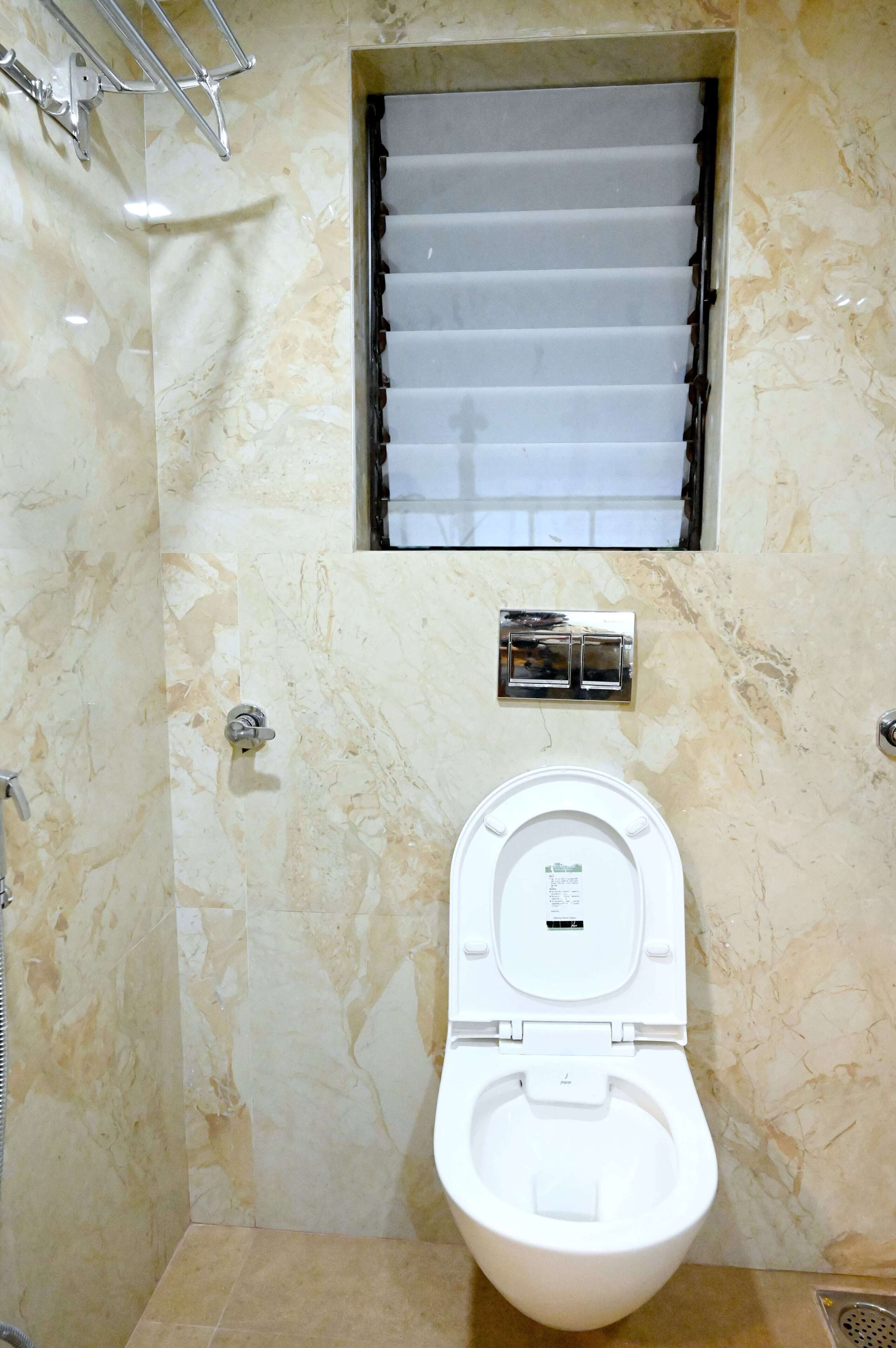 A bathroom with a toilet, a towel rack, and a window with blinds.