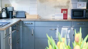 A modern kitchen with grey cabinets, a microwave, a toaster, and a coffee maker.