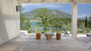 A modern outdoor patio with a view of a mountainous landscape and a lake. - High-end Villa Lyra close to Desimi beach with heated pool (Lefkada)
