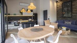 A modern kitchen with a bar area, a dining table with chairs, and a living area with a sofa and a coffee table. - High-end Villa Lyra close to Desimi beach with heated pool (Lefkada)