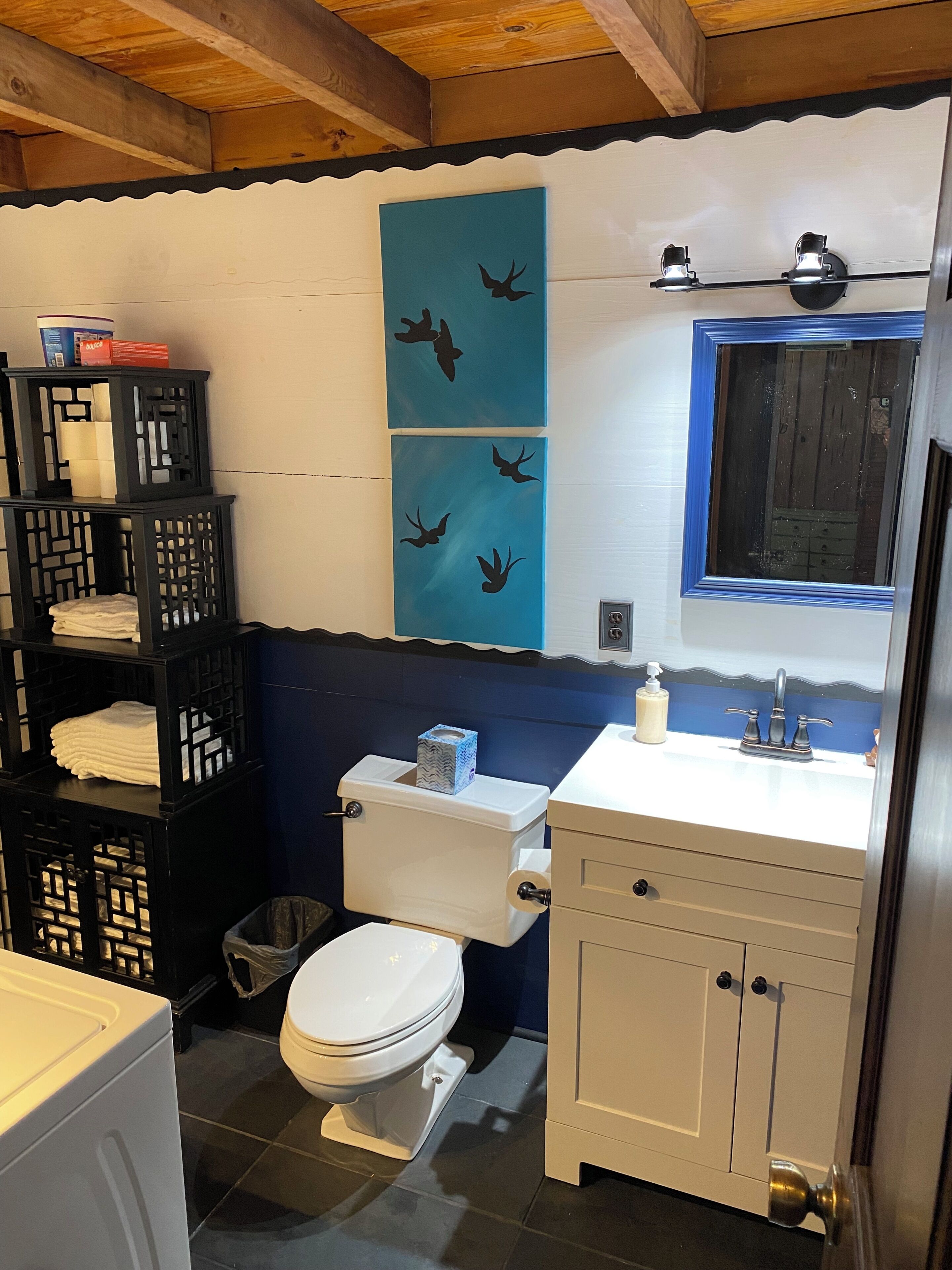 Un baño con inodoro, lavamanos y cestos de ropa apilados.