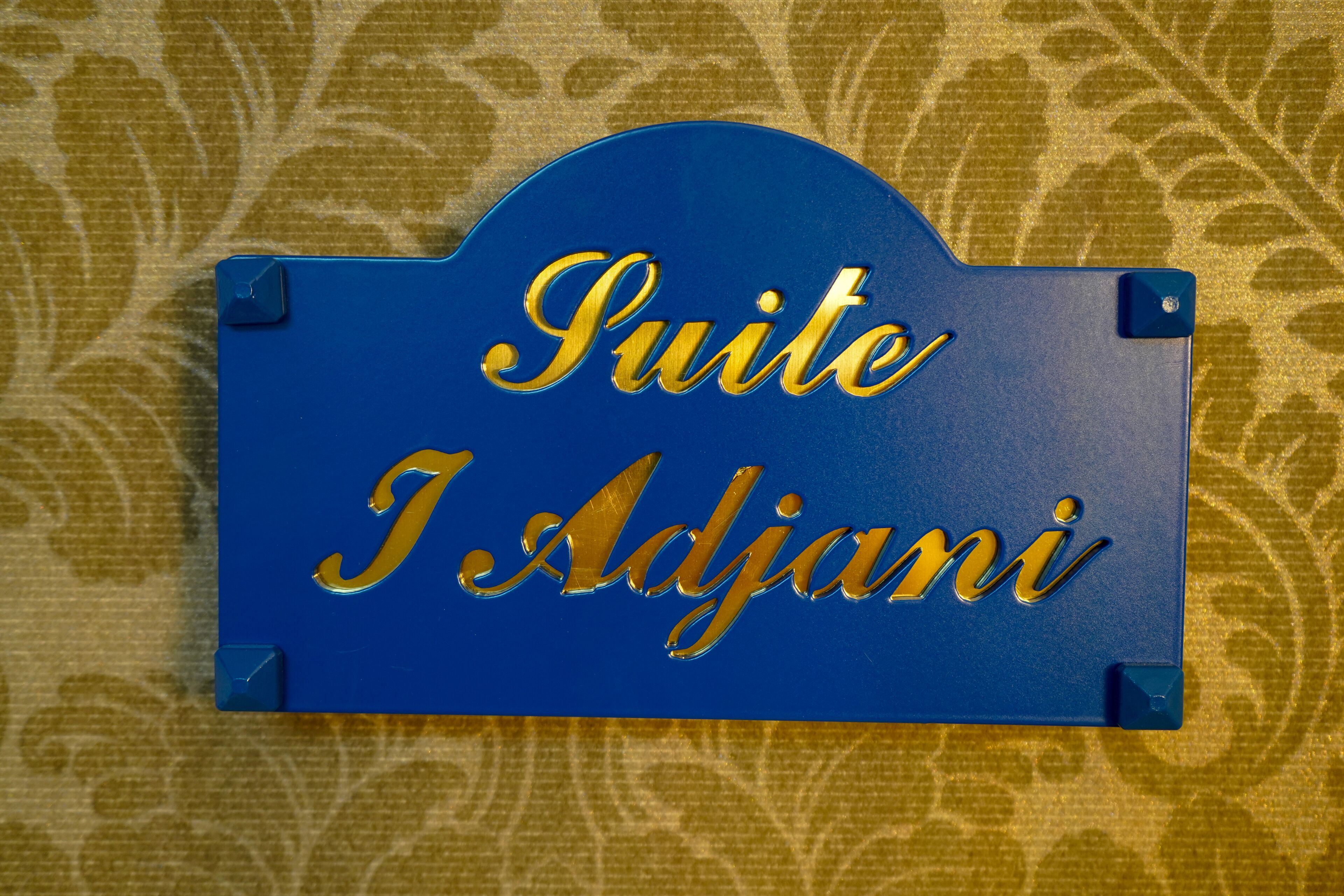 A blue sign with gold lettering that reads "Suite I Adjani."