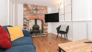 A living room with a stone fireplace, a blue sofa, a wooden coffee table, and a black armchair.