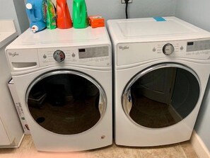 Dos lavadoras Whirlpool de carga frontal, con paneles de control y un estante pequeño arriba.