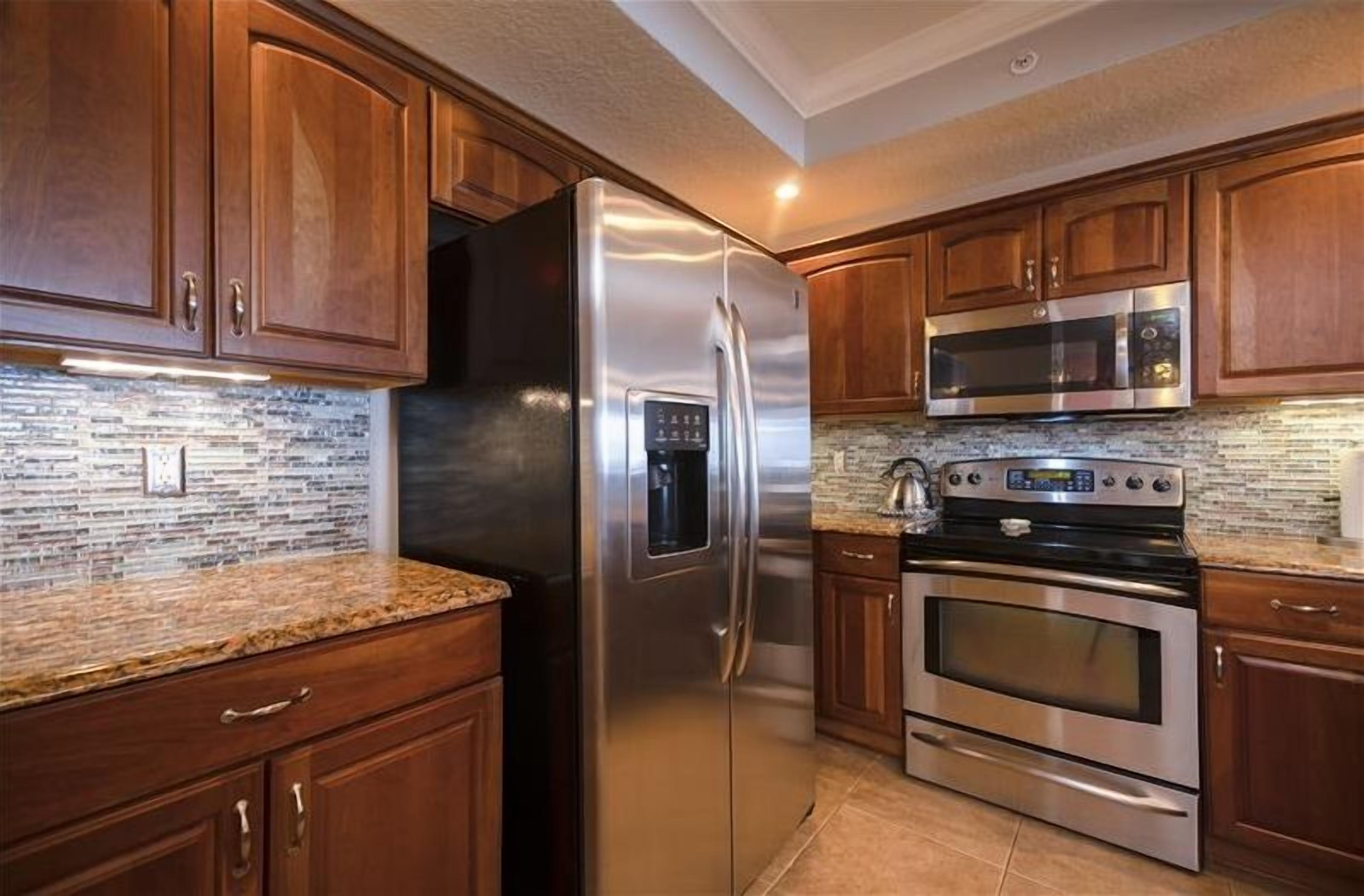 Una cocina con armarios de madera, electrodomésticos de acero inoxidable y salpicadero de azulejos.