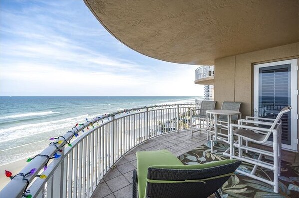 A balcony with a view of the ocean, furnished with a chair and a small table.