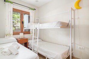 A bunk bed room with a window, a bedside table, and a towel.