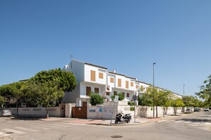 A residential building with a white facade, multiple windows with shutters, and a gated entrance.
