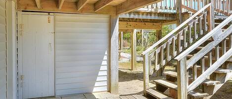 A covered wooden deck with a staircase leading to a higher level.