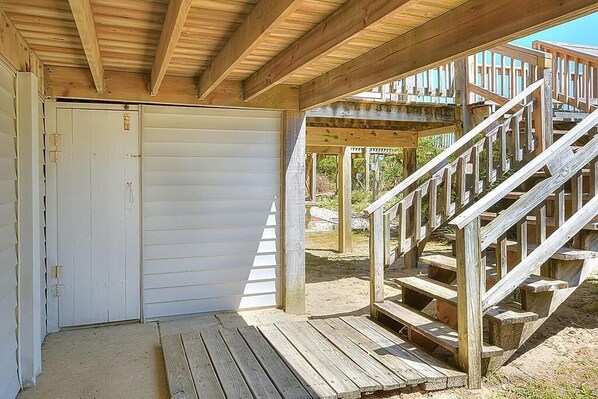 A covered wooden deck with a staircase leading to a higher level.
