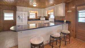 Une cuisine avec des meubles en bois, un îlot central doté de tabourets et un réfrigérateur.