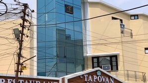 Un edificio con un letrero que dice 'The Tapovan Residency' y otro letrero que indica 'Restaurante'.