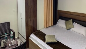 Una habitación de hotel con cama, armario, escritorio con silla y ventilador de techo.