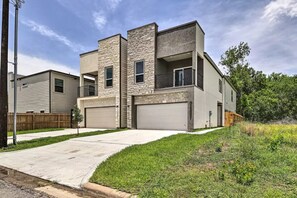 A modern two-story house with a garage, a stone facade, and a small front yard.
