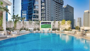 A swimming pool with lounge chairs and a large poster of a soccer match.