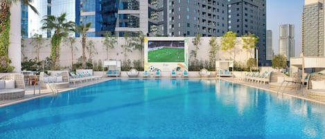 A swimming pool with lounge chairs and a large poster of a soccer match.