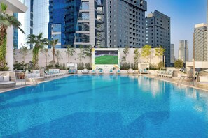 A swimming pool with lounge chairs and a large poster of a soccer match.