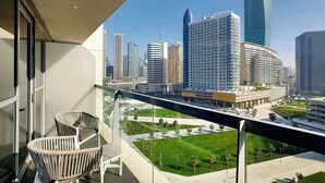 A balcony with wicker chairs, a cityscape view, and a well-maintained lawn.