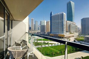 A balcony with wicker chairs, a cityscape view, and a well-maintained lawn.