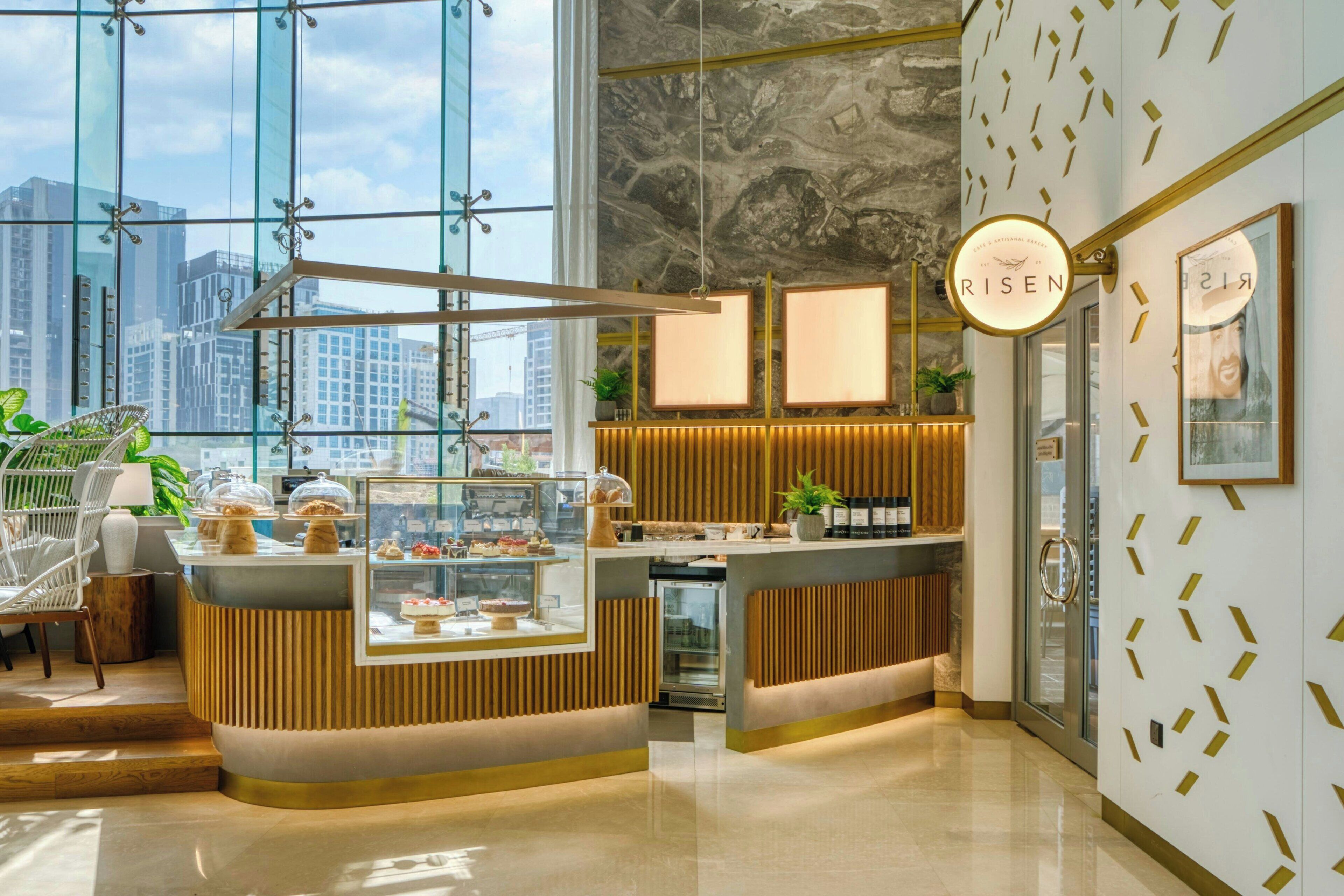 A modern reception area with a glass wall, a wooden reception desk, and a city view.