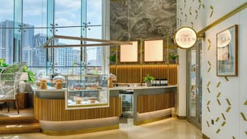 A modern reception area with a glass wall, a wooden reception desk, and a city view.