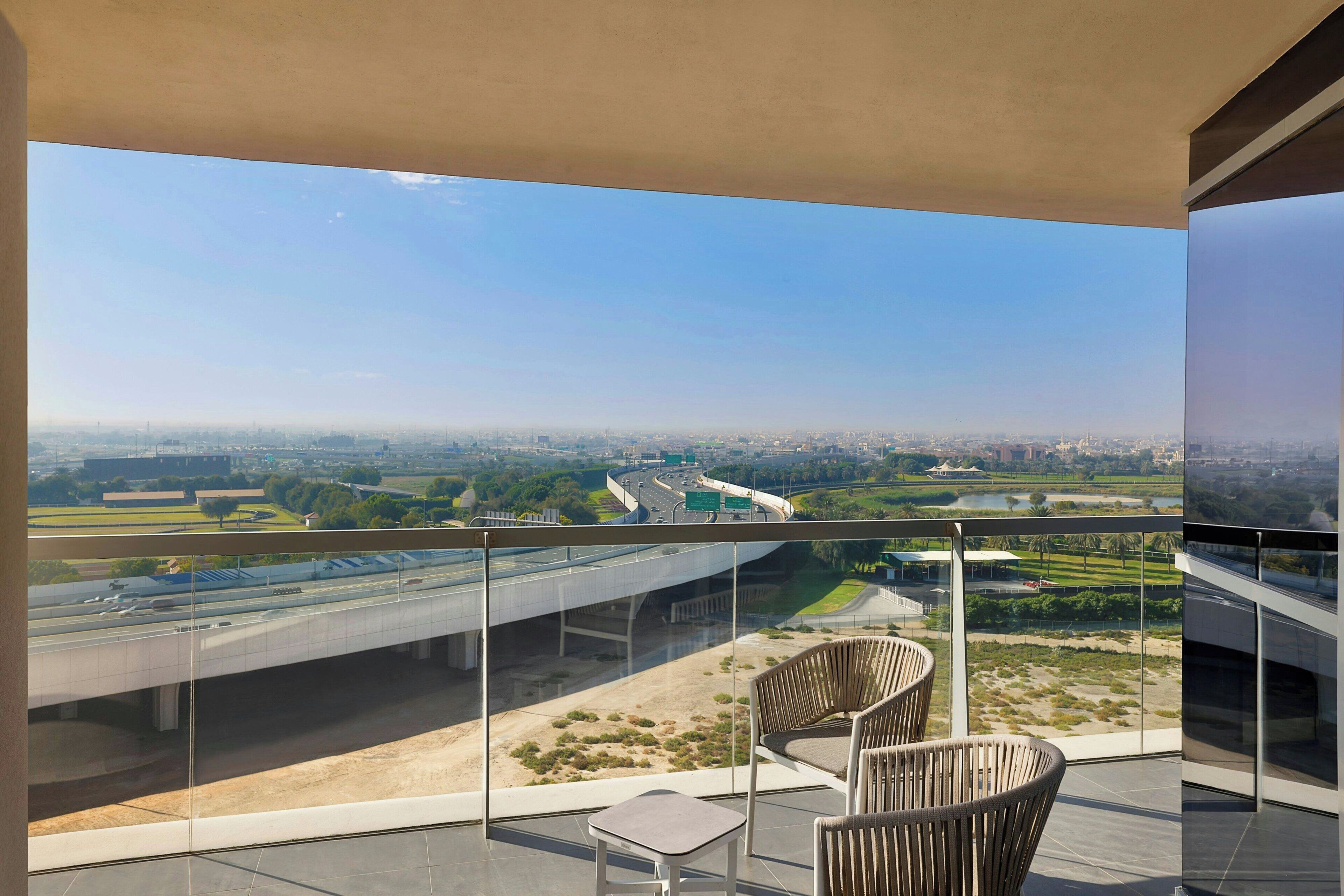 A balcony with a view of a highway and greenery.