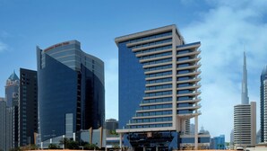A modern cityscape with high-rise buildings, including a distinctive curved building and a tall skyscraper.