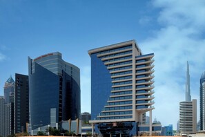 A modern cityscape with high-rise buildings, including a distinctive curved building and a tall skyscraper.