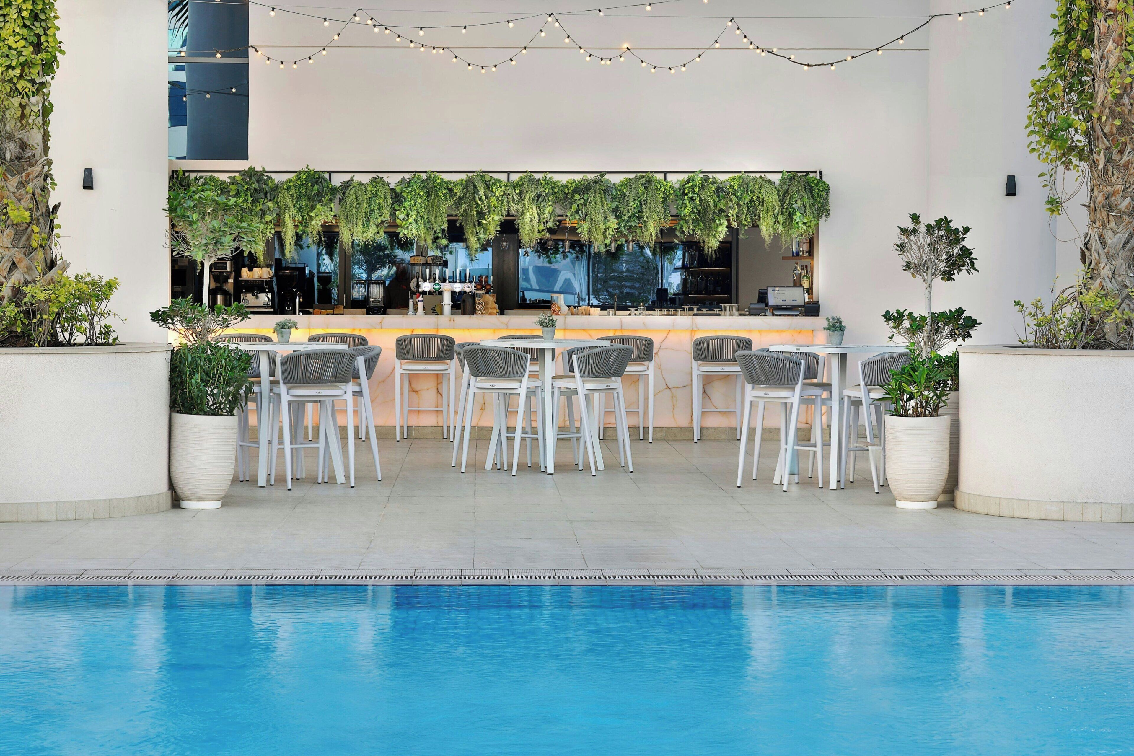 A poolside area with a bar, seating, and greenery.