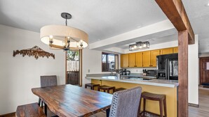 Una cocina moderna con armarios de madera, una isla central y un comedor con mesa y sillas de madera.