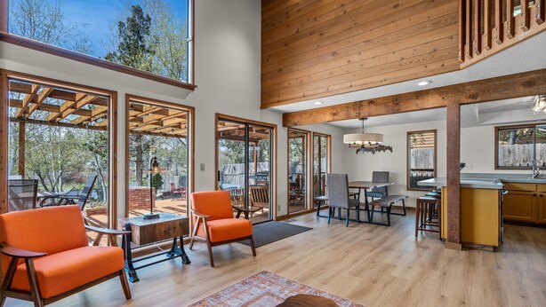 Un salón comedor amplio con ventanas grandes, vigas de madera y una zona de cocina.