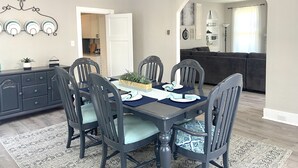 A dining area with a dark wooden table, six chairs, and a hanging light fixture. - New Remodel in St. Charles - Sleeps 10! New patio! Large Fenced-in backyard! (Saint Charles)