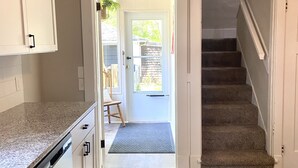 A kitchen with white cabinets, a granite countertop, and a dishwasher. There is a wooden floor and a staircase leading to another level. - New Remodel in St. Charles - Sleeps 10! New patio! Large Fenced-in backyard! (Saint Charles)