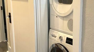 A laundry room with two stacked front-loading washing machines and a white door.