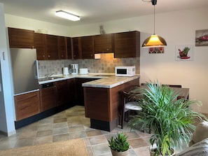 A kitchen with wooden cabinets, a microwave, a coffee maker, and a potted plant. - "Yves am See" Vacation Apartment in the Gaienhofen/Horn Nature Reserve (Gaienhofen)
