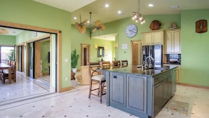 Una cocina con una isla central, un comedor con sillas y un reloj en la pared.