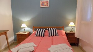 A bedroom with a bed, two bedside tables with lamps, a painting on the wall, and a door. - Hotel Embassy (Miramar)