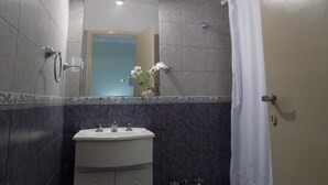 A bathroom with a white sink, a mirror, and a shower curtain. - Hotel Embassy (Miramar)