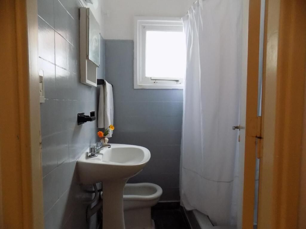 A small bathroom with a sink, toilet, and a window.