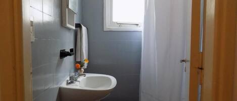 A small bathroom with a sink, toilet, and a window.