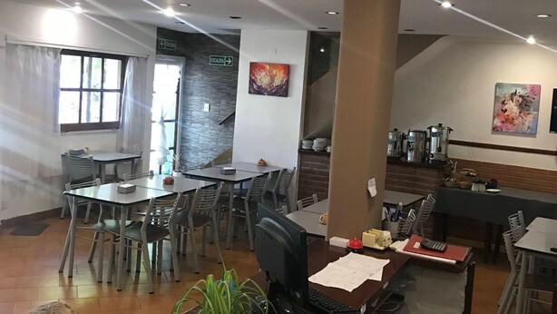 A spacious lobby with a reception desk, multiple dining tables, and a staircase leading to an upper level. - Hotel Embassy (Miramar)