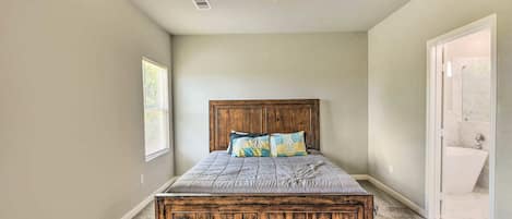 A bedroom with a wooden bed, a ceiling fan, and a bathroom visible through an open door.