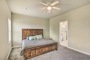 A bedroom with a wooden bed, a ceiling fan, and a door leading to a bathroom.